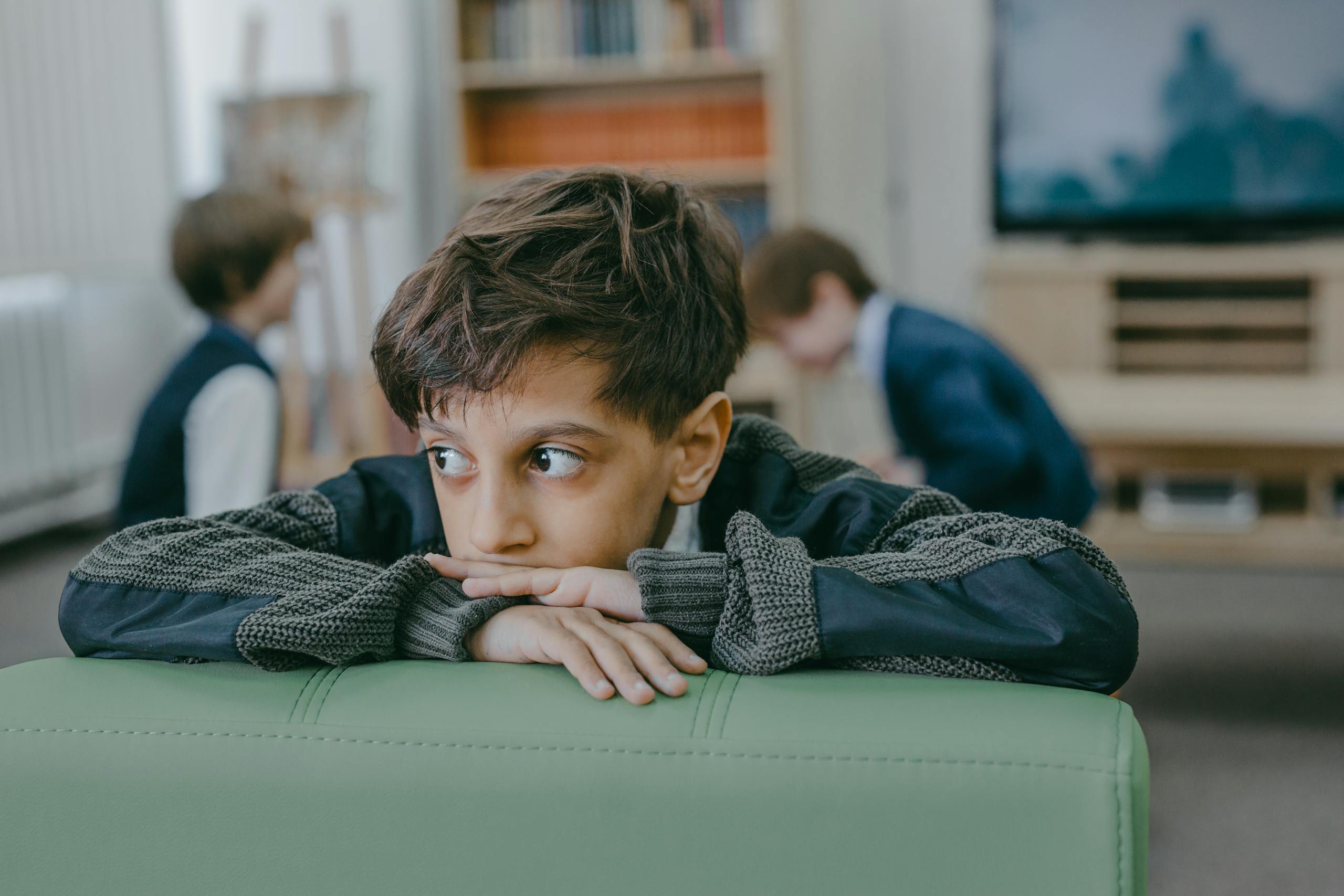 Boy in Black and White Long Sleeve Shirt Sitting on Green Leather Couch