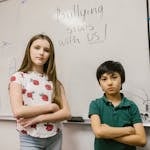 Two Kids Standing by the White Board